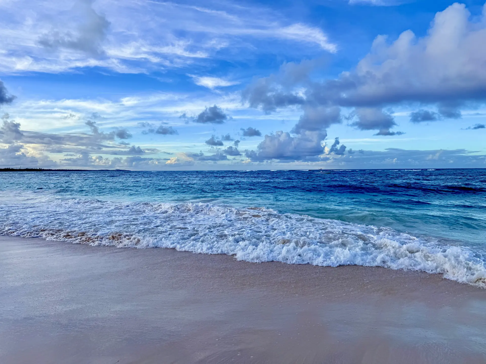 Serene beach shoreline with gentle waves under a bright blue sky